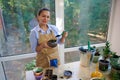 Pleasant stunning Hispanic woman florist enjoys household chores, planting houseplants in the home veranda. Floriculture