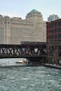 Stunning, Ice chunk covered, frozen Chicago River is aqua blue and runs through Chicago Loop while el train speeds by.