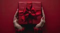 Gift of Love: Woman\'s hands holding luxury box with bow in top down view against a vibrant red backdrop