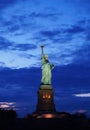 Stunning image of the iconic Statue of Liberty illuminated against a backdrop of cloudy night skies