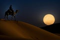 Stunning image of a Tuareg riding a camel in desert at night with full supermoon in the background. Generative Ai