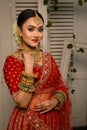 Stunning Indian bride adorned in a traditional red bridal lehenga gracefully wears heavy gold jewelry Royalty Free Stock Photo