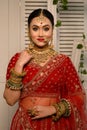 Stunning Indian bride adorned in a traditional red bridal lehenga gracefully wears heavy gold jewelry Royalty Free Stock Photo