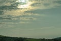 a field with grass and many hills under a sky full of clouds