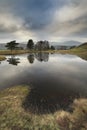 Stunning landscape image of dramatic storm clouds over Kelly Hall Tarn in Lake District during late Autumn Fall afternoon Royalty Free Stock Photo