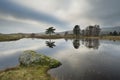 Stunning landscape image of dramatic storm clouds over Kelly Hall Tarn in Lake District during late Autumn Fall afternoon Royalty Free Stock Photo