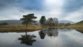 Stunning landscape image of dramatic storm clouds over Kelly Hall Tarn in Lake District during late Autumn Fall afternoon Royalty Free Stock Photo