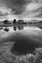 Stunning landscape image of dramatic storm clouds over Kelly Hall Tarn in Lake District during late Autumn Fall afternoon Royalty Free Stock Photo