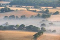 Glorious landscape image of layers of mist rolling over South Downs National Park English countryside during misty Summer sunrise Royalty Free Stock Photo