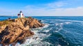 Stunning lighthouse of Maine aerial on rocky island with morning light and waves crashing on coasts