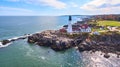 Stunning lighthouse on rocky cliffs in Maine from aerial view