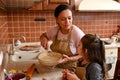 Stunning loving mom pierces rolled out dough, teaches her daughter traditional family culinary while cook pie together