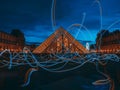 Stunning low-light shot of a long exposure of vibrant lights at the entrance of the Louvre Museum