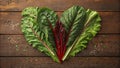 A stunning macro image of green and red leafy vegetables arranged artistically on a wooden table creating the shape of a