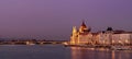 Panoramic view of illuminated grand buildings at the shore near a bridge at sunset