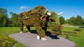 Majestic monument of a bull cow made from flowers in a lash green park environment