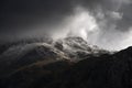Stunning moody dramatic Winter landscape image of snowcapped Tryfan mountain in Snowdonia with stormy weather brooding overhead Royalty Free Stock Photo