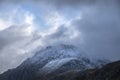 Stunning moody dramatic Winter landscape image of snowcapped Tryfan mountain in Snowdonia with stormy weather brooding overhead Royalty Free Stock Photo