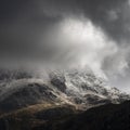 Stunning moody dramatic Winter landscape image of snowcapped Tryfan mountain in Snowdonia with stormy weather brooding overhead Royalty Free Stock Photo