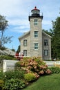 Gorgeous stone lighthouse with light blue windows ands garden of flowering bushes, Sodus Point, New York, summer 2022