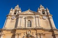 Stunning, ornate church building boasting two clocks atop its facade in Mdina Old City Fortress Royalty Free Stock Photo