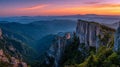 Stunning panoramic view of rugged mountain cliffs and dense forest valleys under a vibrant sunset sky with layered distant hills Royalty Free Stock Photo