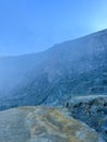 Stunning panoramic views of the Ijen Crater with large rocks and a bright blue sky in the background