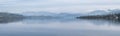 Stunning peaceful landscape image of misty Spring morning over Windermere in Lake District and distant misty peaks