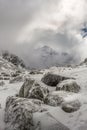 Stunning peak in the clouds and beautiful ice flowers on the rocks after a winter storm at the Rila mountain in Bulgaria,