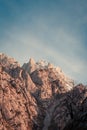 Stunning peak of the rocky mountain with pink tones over a cloudy sky