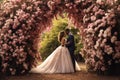 A stunning photo capturing a bride and groom standing together in front of a beautiful floral archway during their wedding