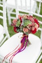 Stunning red bridal bouquet on white chair. Wedding ceremony. Mix of succulents, orchids and roses Royalty Free Stock Photo