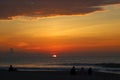 A stunning red and yellow sunrise over the vast ocean with waves rolling into the shore and people on the beach in Carolina Beach Royalty Free Stock Photo