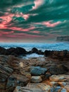 Stunning sandy beach with a cluster of rocks in foreground, illuminated by a bright and vibrant sky Royalty Free Stock Photo