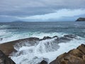 Stunning seascape with foamy waves hitting the rocks of the seashore, cumulative clouds in the sky