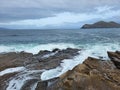 Stunning seascape with foamy waves hitting the rocks of the seashore, cumulative clouds in the sky