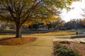 A stunning shot of an autumn landscape in the park with a still lake, people walking, gorgeous autumn colored trees with blue sky