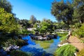 A stunning shot of a green lake with a stone bridge and buildings with Chinese architecture surrounded with lush green trees Royalty Free Stock Photo