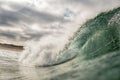 Stunning shot of a large, emerald-green wave crashing during gloomy weather