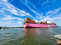 A stunning shot of a large pink container ship sailing down the Savannah River with vast blue river water