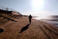 A stunning shot of a male walking along the beach dressed in winter attire on a freezing cold winter morning