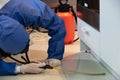 Stunning shot of a professional exterminator spraying a chemical under a kitchen counter