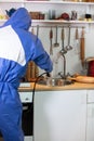 Stunning shot of a professional pest exterminator spraying a chemical on a kitchen sink