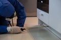 Stunning shot of a professional pest exterminator spraying a chemical under a kitchen counter