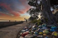 A stunning shot of a rock memorial along a bike path at the beach with colorful rocks and lush green trees with blue sky Royalty Free Stock Photo