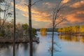 A stunning shot of the still blue waters of the lake at Stone Mountain park with lush green and autumn colored trees reflecting of