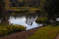 A stunning shot of a still lake in the park surrounded by lush green and autumn colored trees reflecting off the water Royalty Free Stock Photo