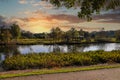 A stunning shot of a still lake in the park surrounded by lush green and autumn colored trees reflecting off the water Royalty Free Stock Photo