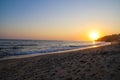 A stunning shot of the sunset and the ocean and the rock and people walking on the beach at El Matador beach