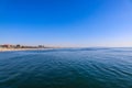 A stunning shot of the vast deep blue rippling ocean water with miles of sandy beach with people relaxing in the sand and hotels Royalty Free Stock Photo